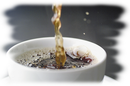 Weisse Tasse mit fliesendem Kaffee in der Tasse