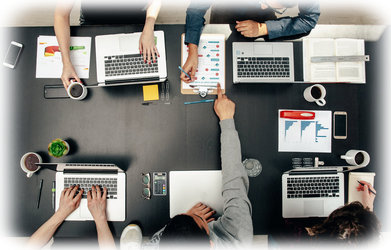 5 Personen in tech-gruppenbesprechung an einem Tisch und drei Tassen Kaffee mit Aufnahme von oben.